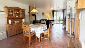 Un comedor con una mesa y sillas de madera, un mueble con puertas de vidrio y una estufa al fondo.