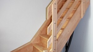 A wooden staircase with a handrail and a vacuum cleaner on the floor. - Experience Tranquility at Ferienwohnung Vadders Hof in Risum-Lindholm! (Risum-Lindholm)