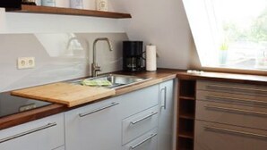 A modern kitchen with a wooden countertop, a sink, and a window above the sink. - Experience Tranquility at Ferienwohnung Vadders Hof in Risum-Lindholm! (Risum-Lindholm)