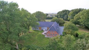 A house with a sloped roof, surrounded by dense greenery and trees. - "Experience Tranquility and Adventure in Ole Hof Risum-Lindholm!" (Risum-Lindholm)