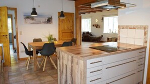 A kitchen with wooden cabinets, a central island, and a dining area with chairs and a table. - "Experience Tranquility and Adventure in Ole Hof Risum-Lindholm!" (Risum-Lindholm)