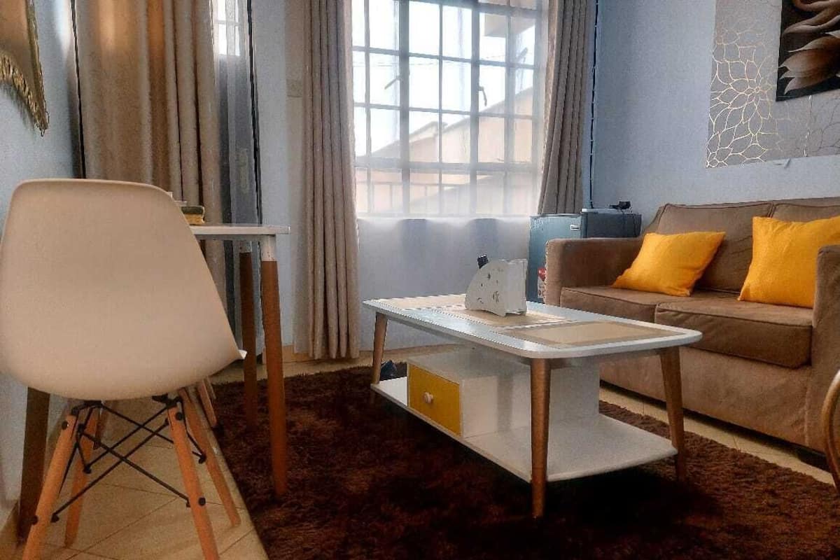 Ein modernes Wohnzimmer mit einem weißen Couchtisch, einem braunen Sofa mit gelben Kissen und einem weißen Sessel.