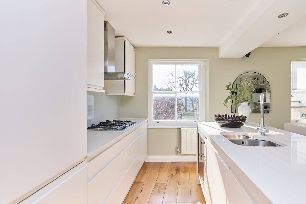 A modern kitchen with white cabinetry, a gas stove, a window, and a sink.