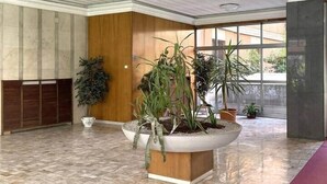 A spacious lobby with a high ceiling, large windows, and multiple potted plants. - Sandrine - your comfy stay (Bologna)