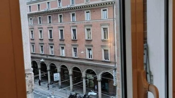 A view from a window overlooking a street with a building featuring multiple floors and a series of arches. - Sandrine - your comfy stay (Bologna)