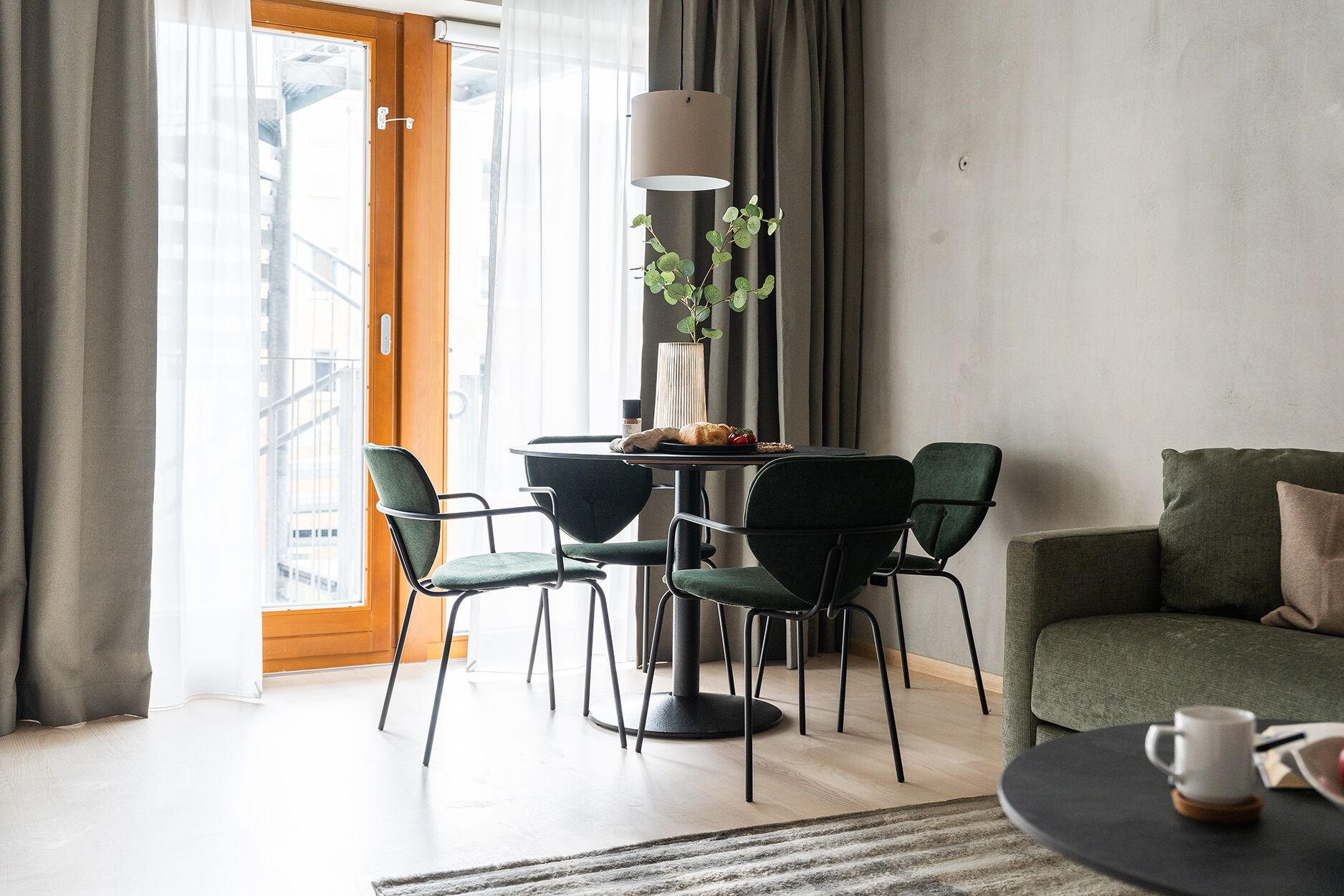 Un salon moderne avec un coin repas, comprenant une table ronde avec des chaises, un canapé, une lampe et une plante.