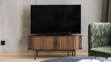 A modern living room with a flat-screen TV on a wooden cabinet, a green upholstered chair, and a book on a table.