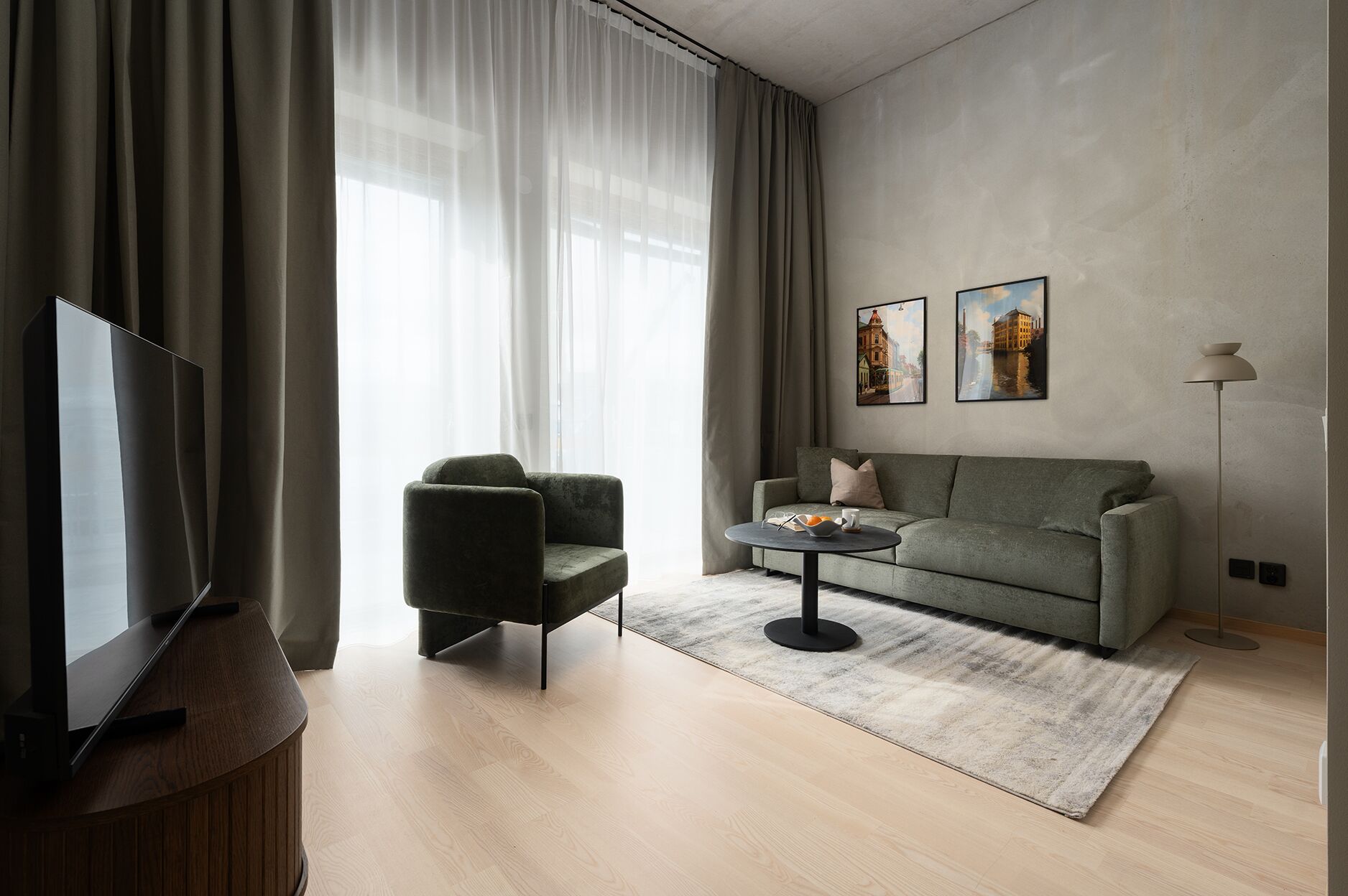 Un salon moderne avec un canapé, un fauteuil, une table basse et des œuvres d’art accrochées au mur.