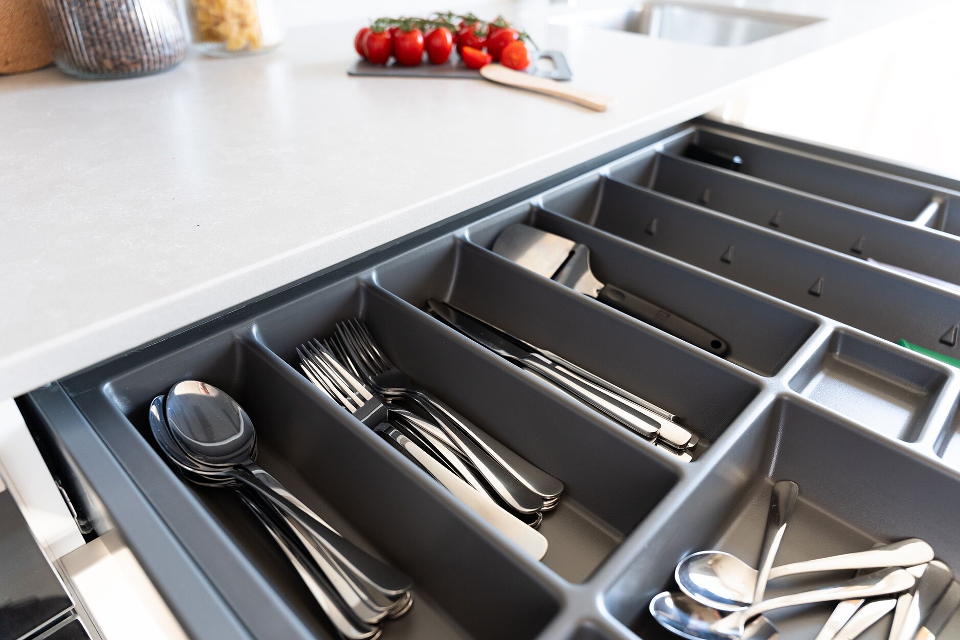 Un cajón de cocina con utensilios organizados en compartimentos.
