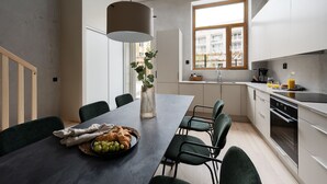 Une cuisine moderne avec un coin repas, comprenant une grande table, des chaises et une fenêtre donnant sur des immeubles.
