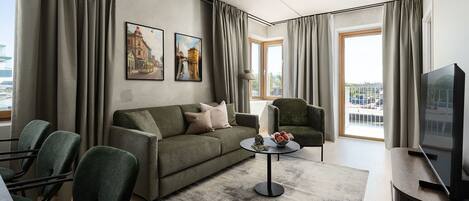 Una sala de estar moderna con un sofá, sillones, una mesa de centro y un televisor.