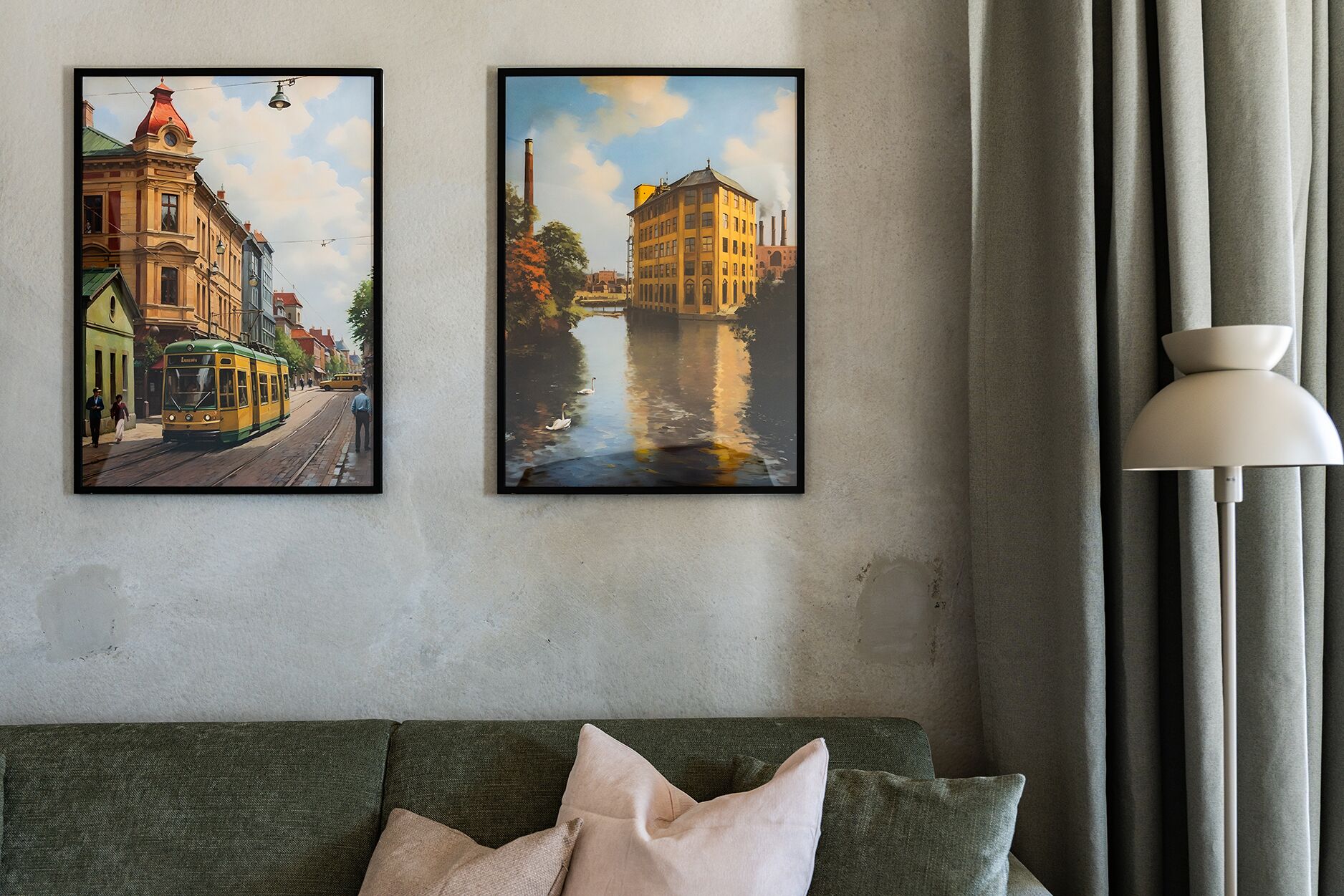 Two framed paintings of urban scenes on a wall, a lamp, and a green sofa with cushions.