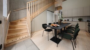 Une cuisine moderne avec un coin repas, agrémentée d’un escalier en bois et arborant un design minimaliste.