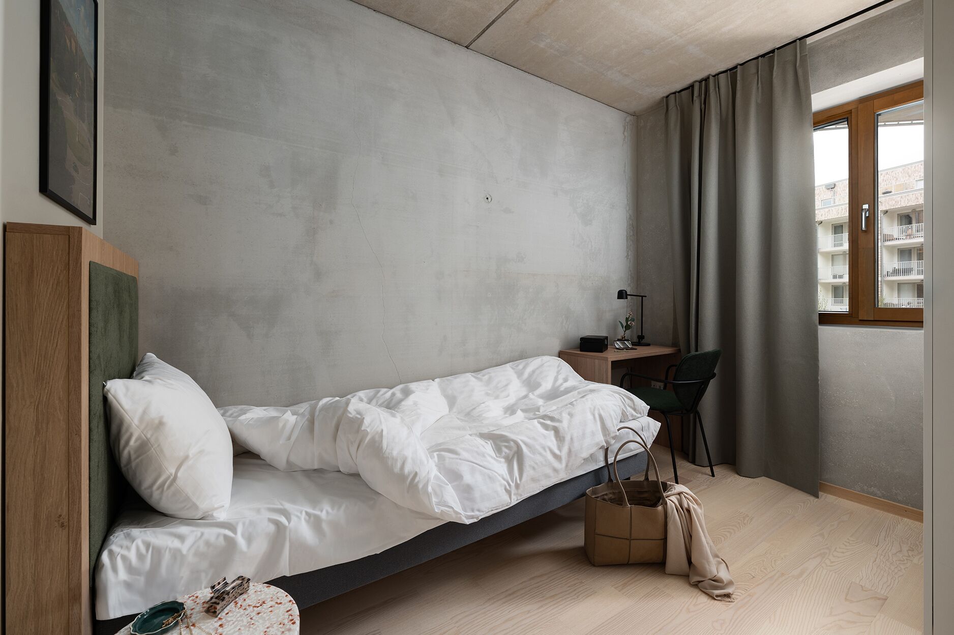 Een minimalistische slaapkamer met een bed, bureau en stoel.