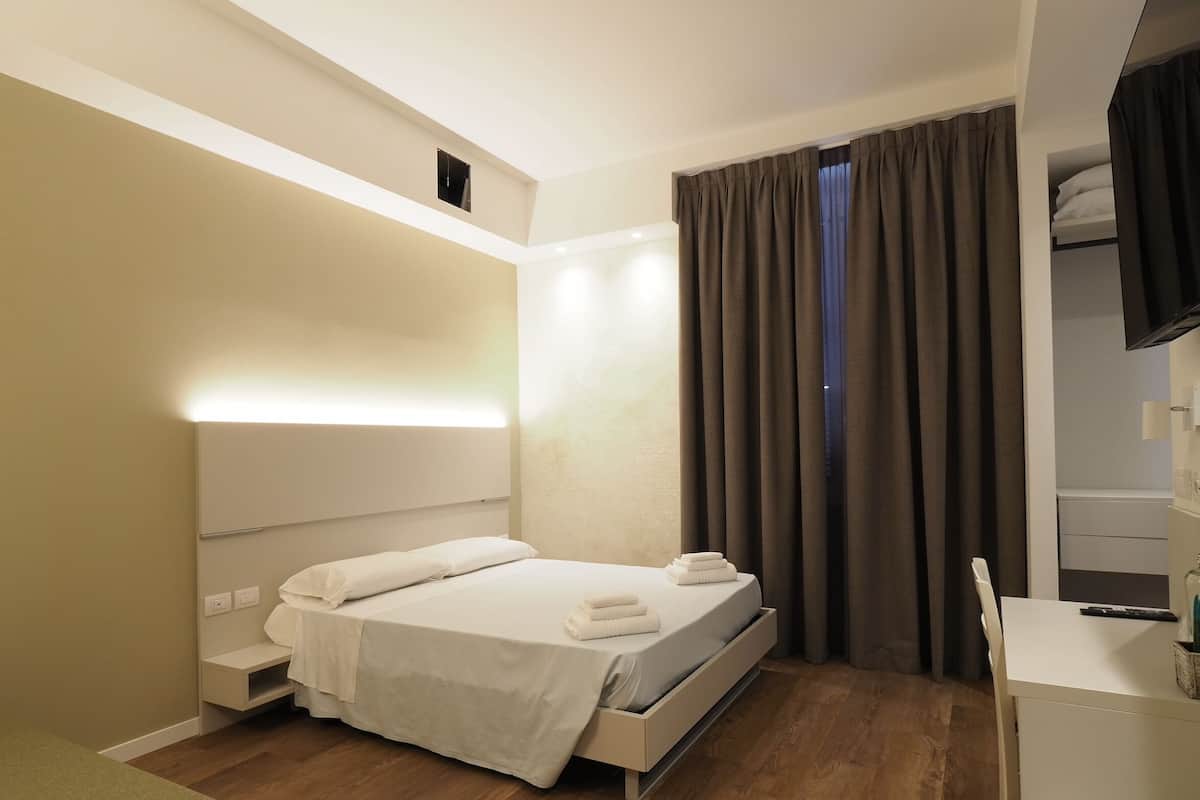 Ένα σύγχρονο υπνοδωμάτιο με ένα κρεβάτι, ένα κομοδίνο και μια τηλεόραση.