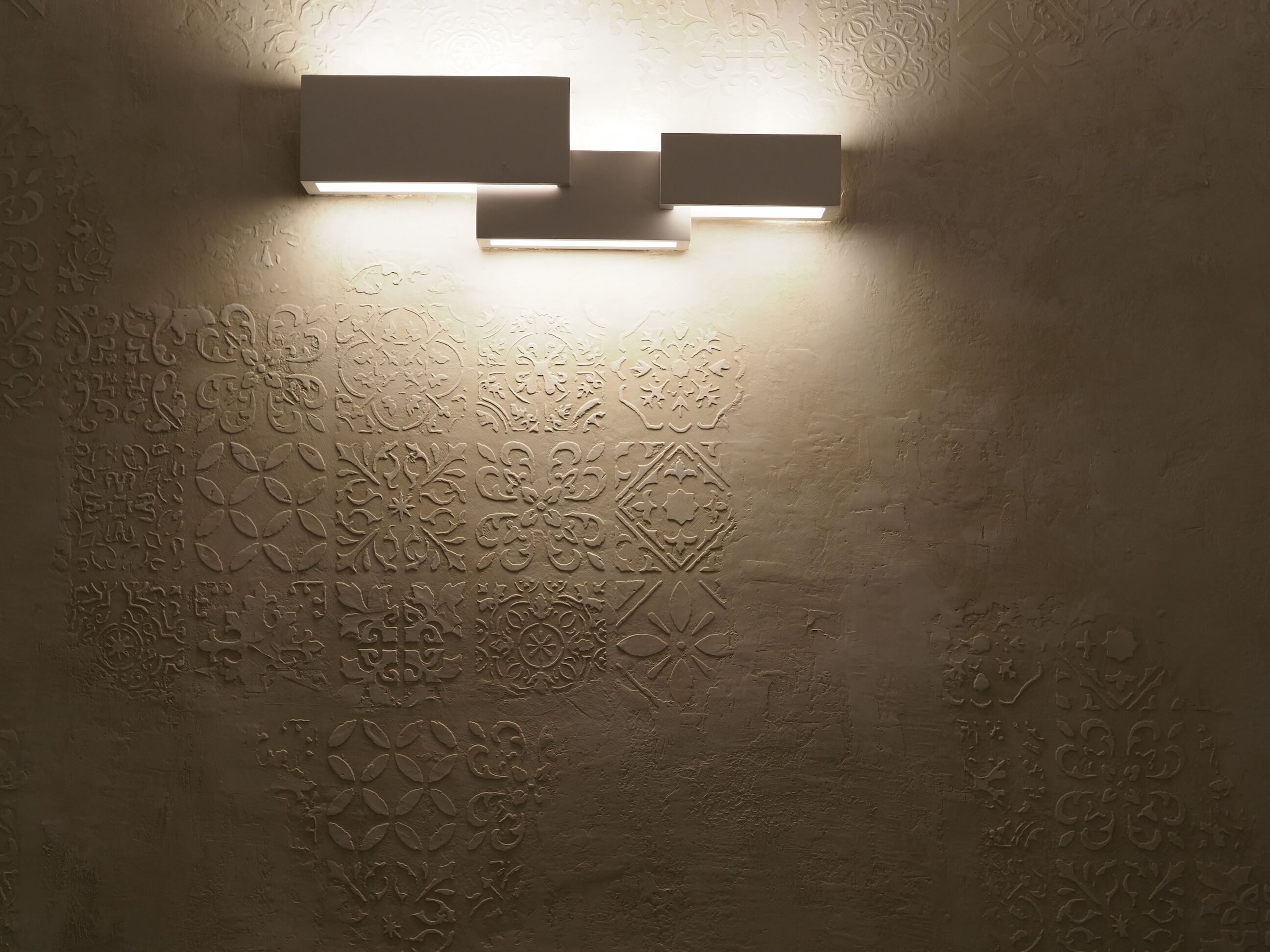 Un mur orné de motifs en relief décoratifs et deux appliques rectangulaires.