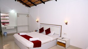Une chambre d’hôtel avec un grand lit, une table de chevet, une commode, un miroir et une armoire.