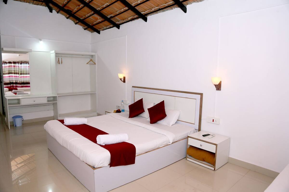Una habitación de hotel con una cama grande, una mesita de noche, un armario y un espejo.