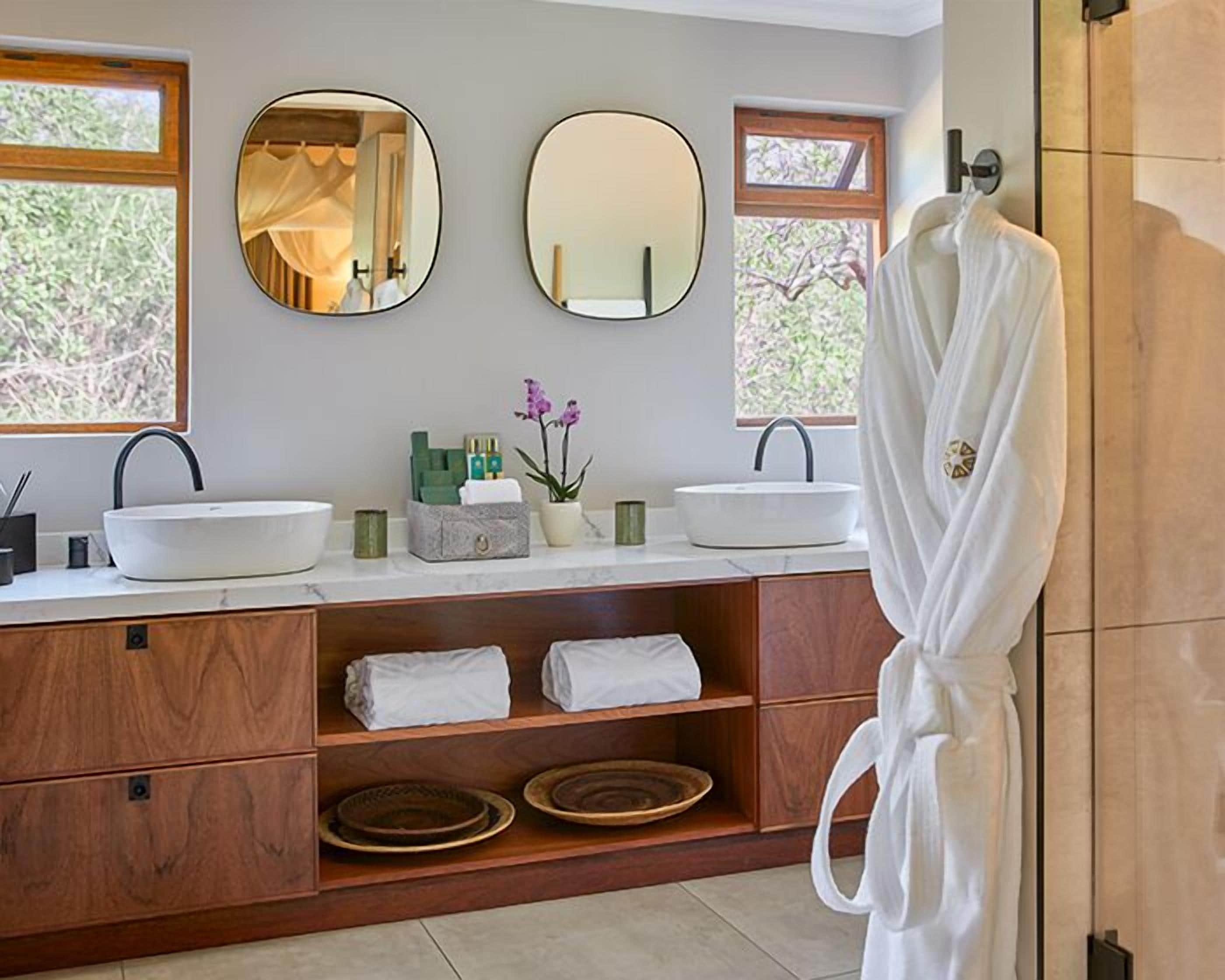 Un baño moderno con dos lavamanos, un perchero para batas y un mueble de tocador con espacio de almacenamiento.