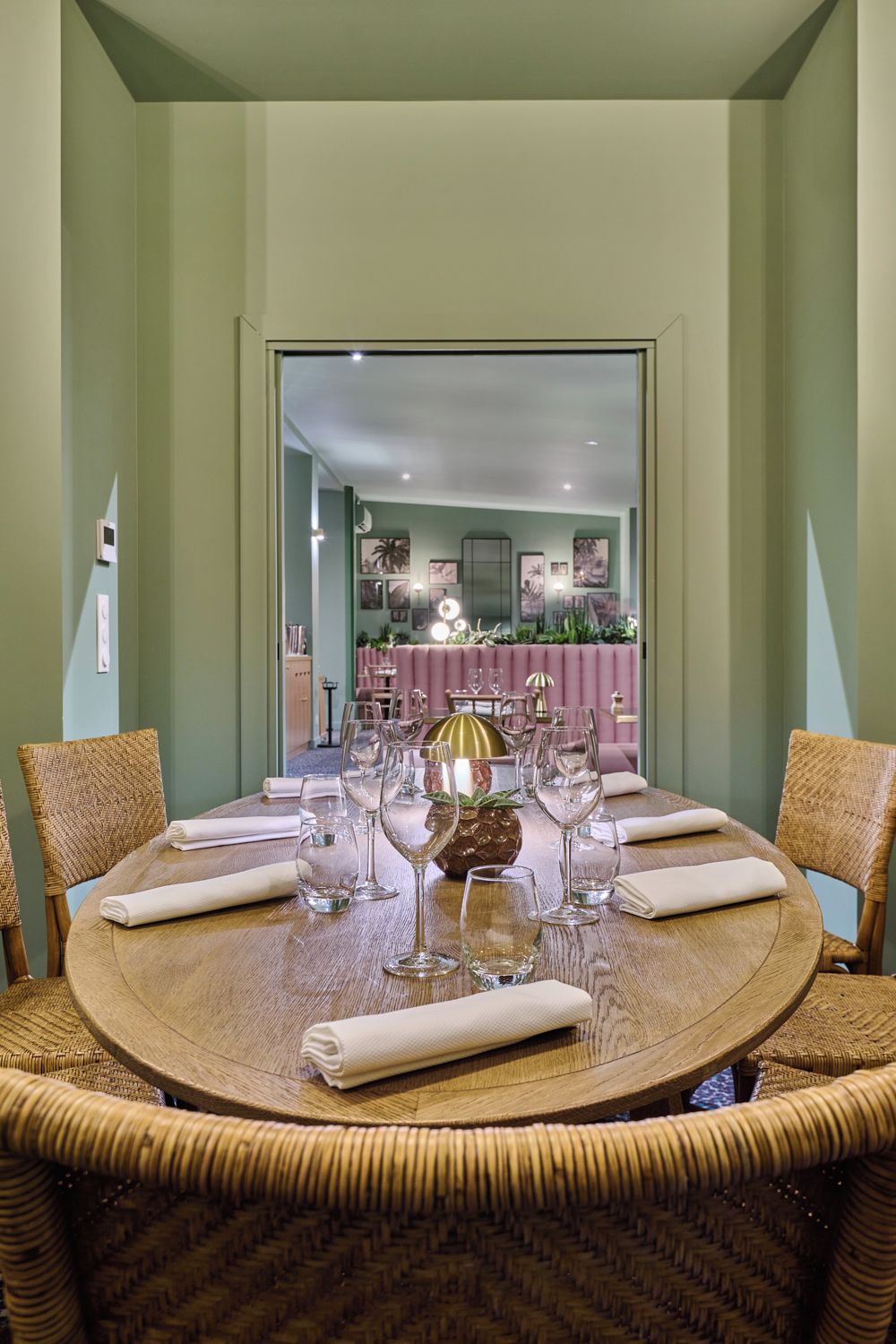 A round dining table with a central decorative item, surrounded by wicker chairs.