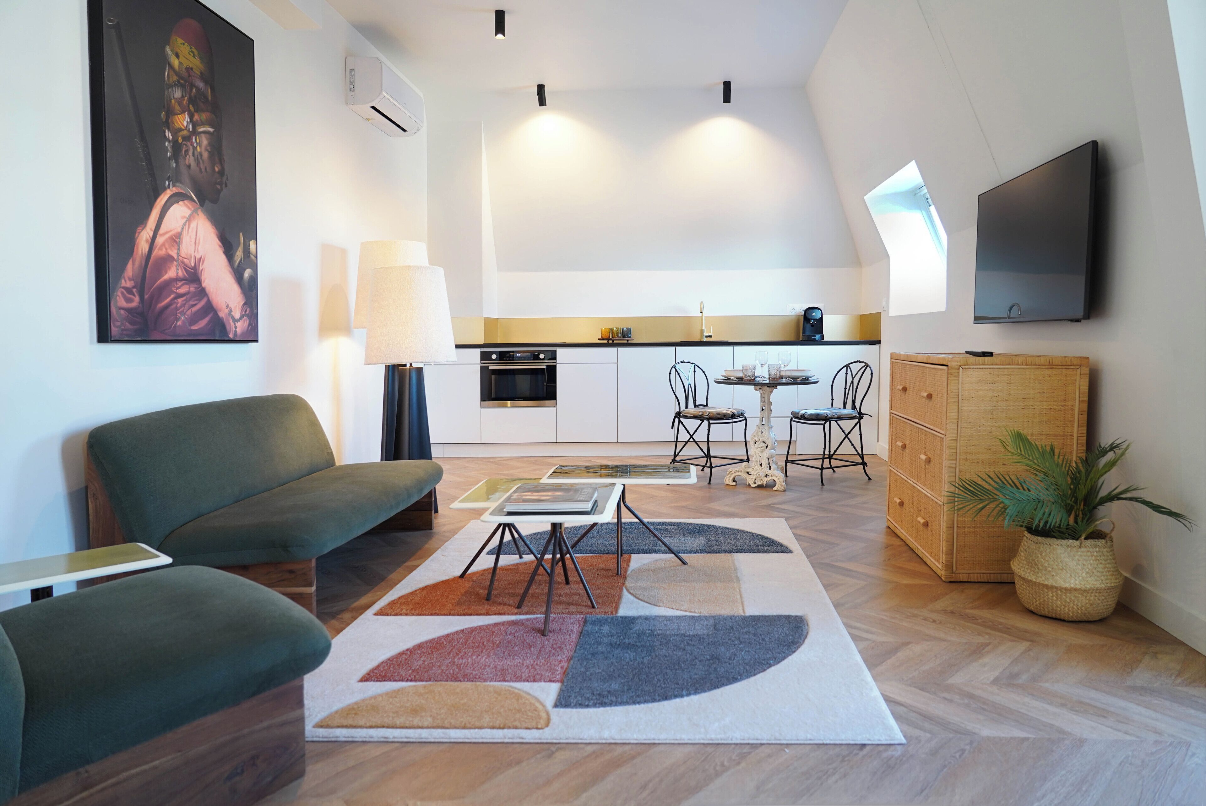 Una sala de estar moderna con un sofá, una mesa de centro y un televisor. Se observa una cocina al fondo, junto a un comedor.