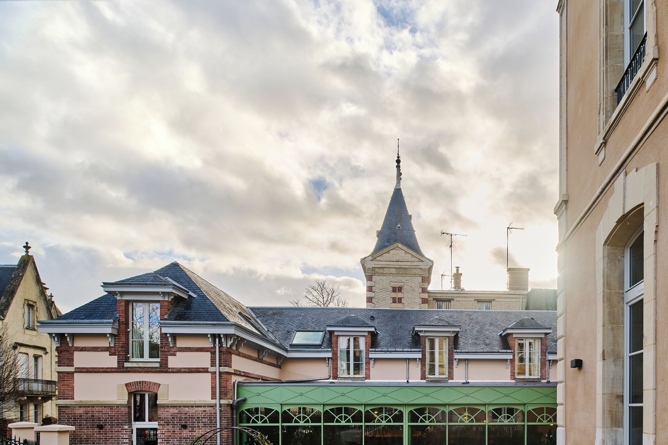 A traditional European-style building with a prominent tower, a green awning, and a brick facade.
