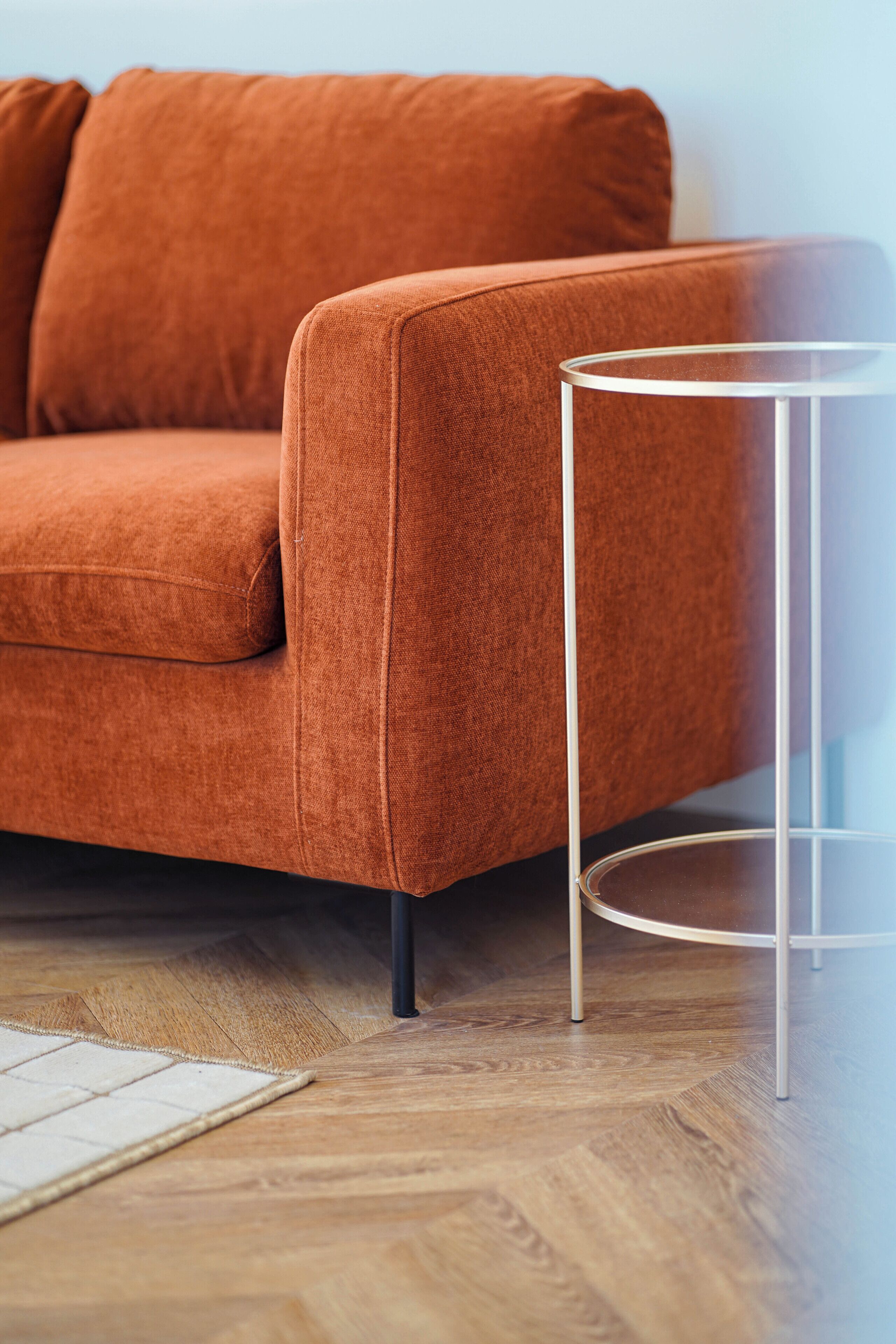 Une pièce avec un canapé marron et une petite table d’appoint en verre transparent.