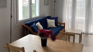 A room with a wooden dining table, blue sofa, and a ceiling fan. - APARTMENT IN CALA'N FORCAT (Los Delfines)