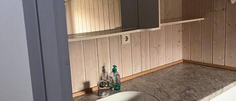 A bathroom with a white sink, wooden cabinets, and a mirror above the sink.