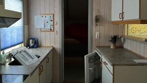 Eine kleine Küche mit Holzwänden, einem Spülbecken, einem Kühlschrank und einer Arbeitsfläche.