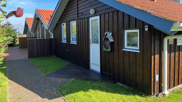 Ein Gebäude aus Holz mit geneigtem Dach, einer Tür und einem Fenster.
