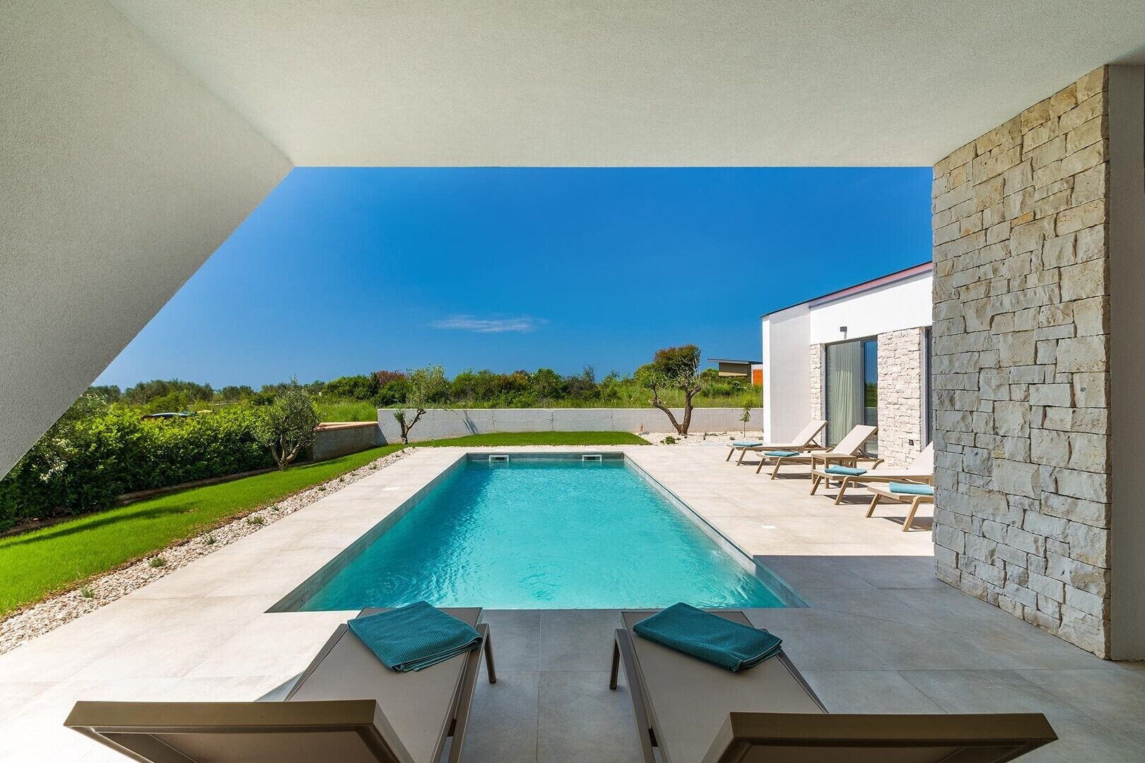 Ein rechteckiger Pool mit Liegestühlen und einer Steinmauer.