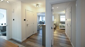 A modern interior with a hallway leading to a bedroom, a bathroom, and a living area with a sofa and table. - Barassie Bay View apartment (Troon)