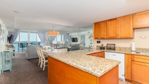 A modern kitchen with wooden cabinets, granite countertops, and a central island. - Sunset Selfies & Seaside Memories | Bayfront OCMD Retreat (Ocean City)