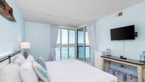 A bedroom with a bed, a desk, a TV, and a window with curtains. - Sunset Selfies & Seaside Memories | Bayfront OCMD Retreat (Ocean City)