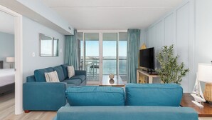 Un salon moderne avec un canapé, un téléviseur et une vue sur la mer.