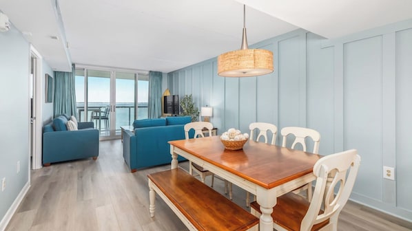 A modern living room with a dining table, blue sofas, and a view to the outside.