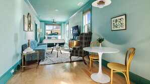 Een kamer met turquoise wanden, een bed, een bureau, een stoel, een tafel en een lamp.