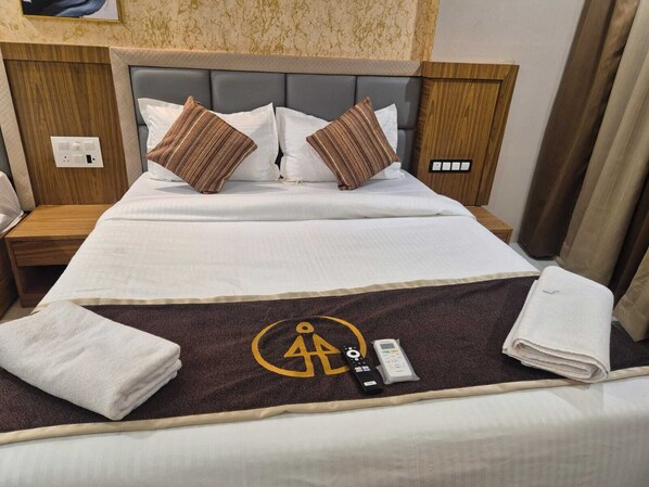 A hotel room with a bed, two pillows, a remote control, and a towel on the bed.