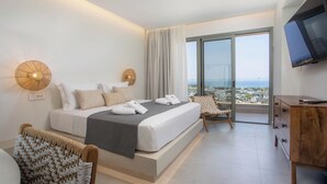 A modern hotel room with a large bed, a flat-screen TV, a wooden dresser, and a view of the city through large windows.