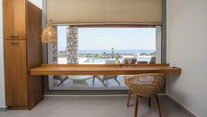 A balcony with a wooden desk, wicker chair, and a view of the sea.