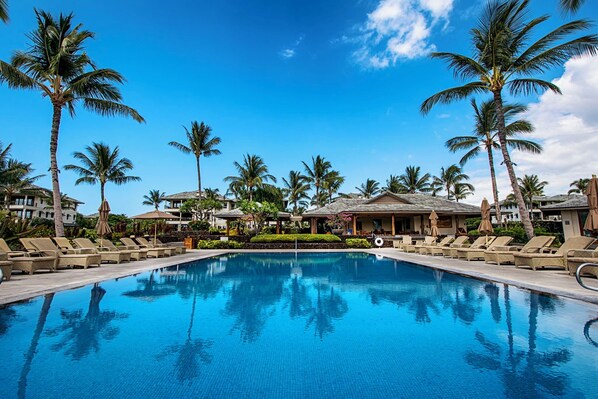A swimming pool with lounge chairs and palm trees. - 🌴Aloha Moana Penthouse  | Elevator | Ocean View | Beach Access🌴 (Waikoloa)