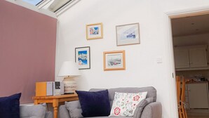 A living room with a sofa, a lamp, and framed pictures on the wall.