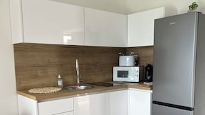 A modern kitchen with white cabinets, a stainless steel refrigerator, a microwave, and a coffee maker. - Apartman Suzzy 2 (Dramalj)
