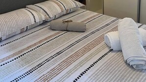 A neatly made bed with striped bedding, a bedside lamp, and a mirror on the wall. - Apartman Suzzy 2 (Dramalj)