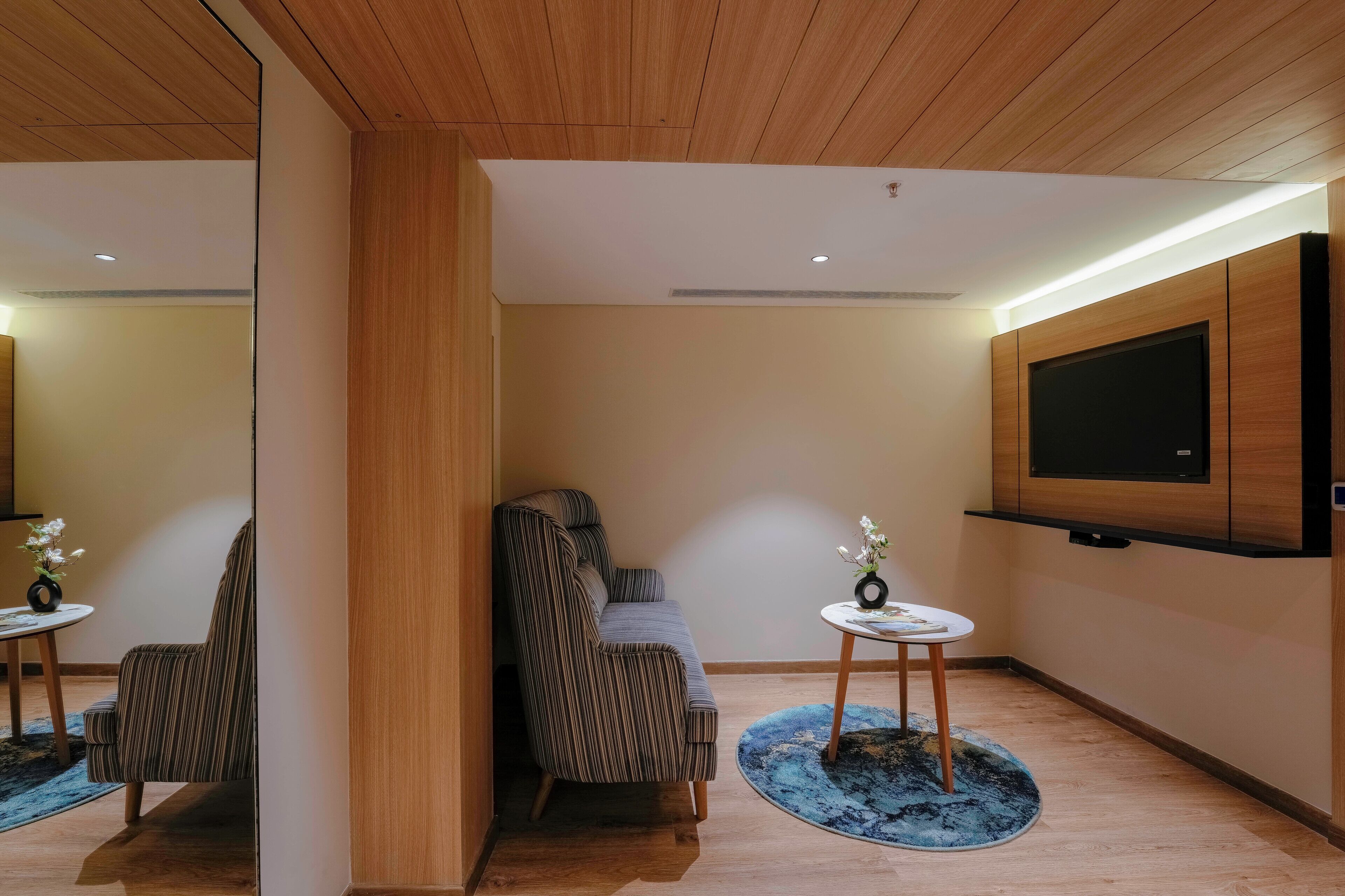 A modern living room with a sofa, a TV mounted on the wall, and a small table with a vase.