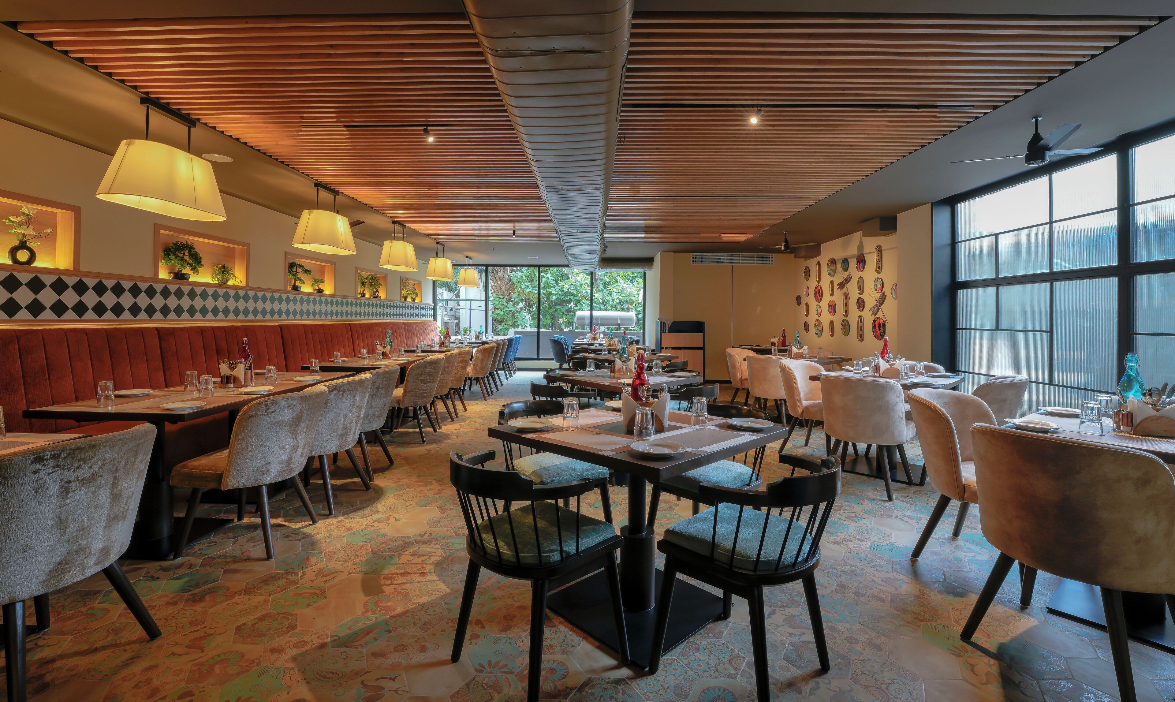 Un restaurant avec des banquettes, des tables et des chaises. Des lampes sont suspendues au plafond, qui est recouvert de lattes de bois.