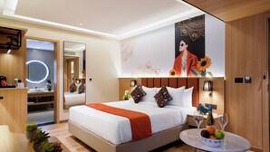 A modern hotel room with a large bed, bedside table with wine glasses, a mirror, and a wall with a poster. - TGI Oberon  (Bengaluru)