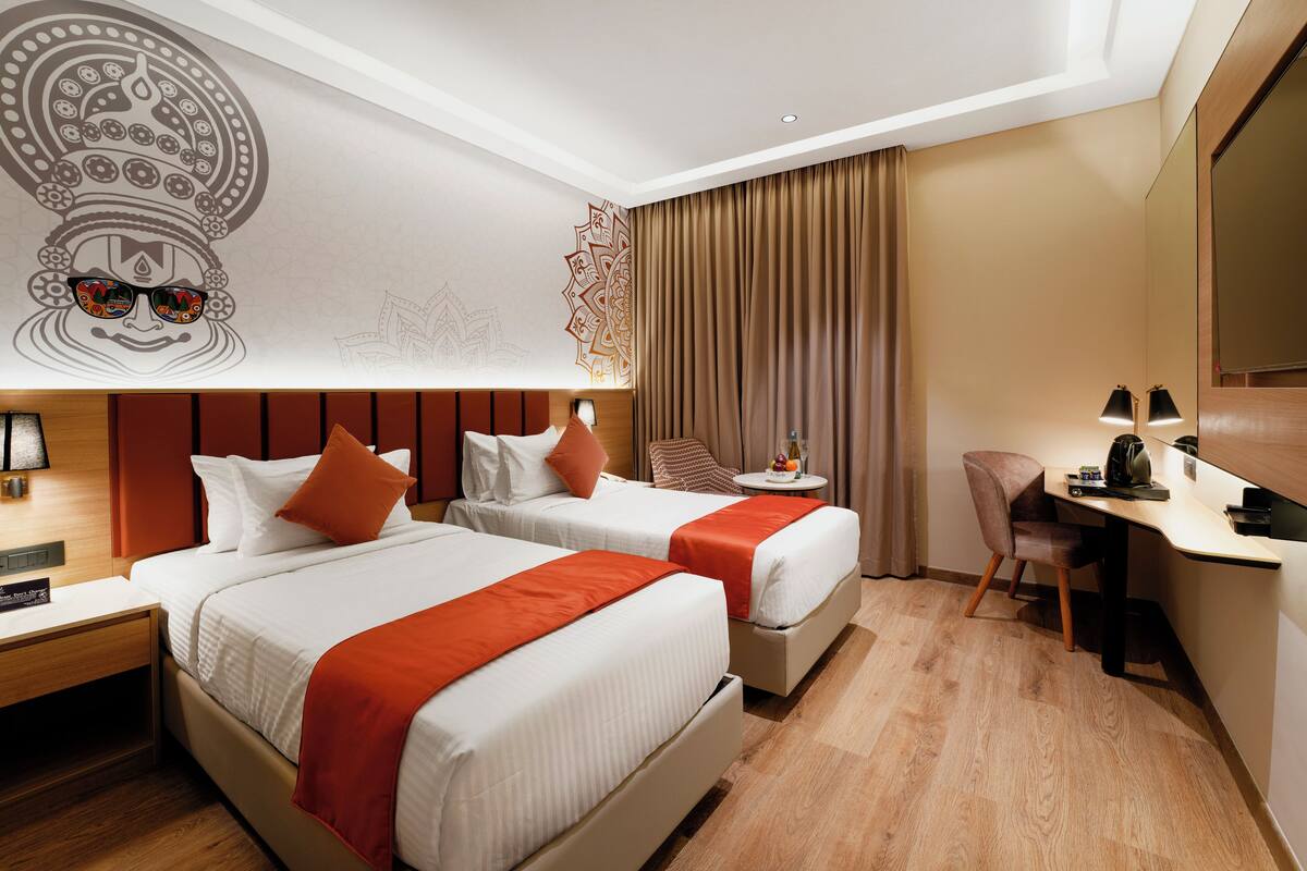 A hotel room with two beds, a desk, and a chair.