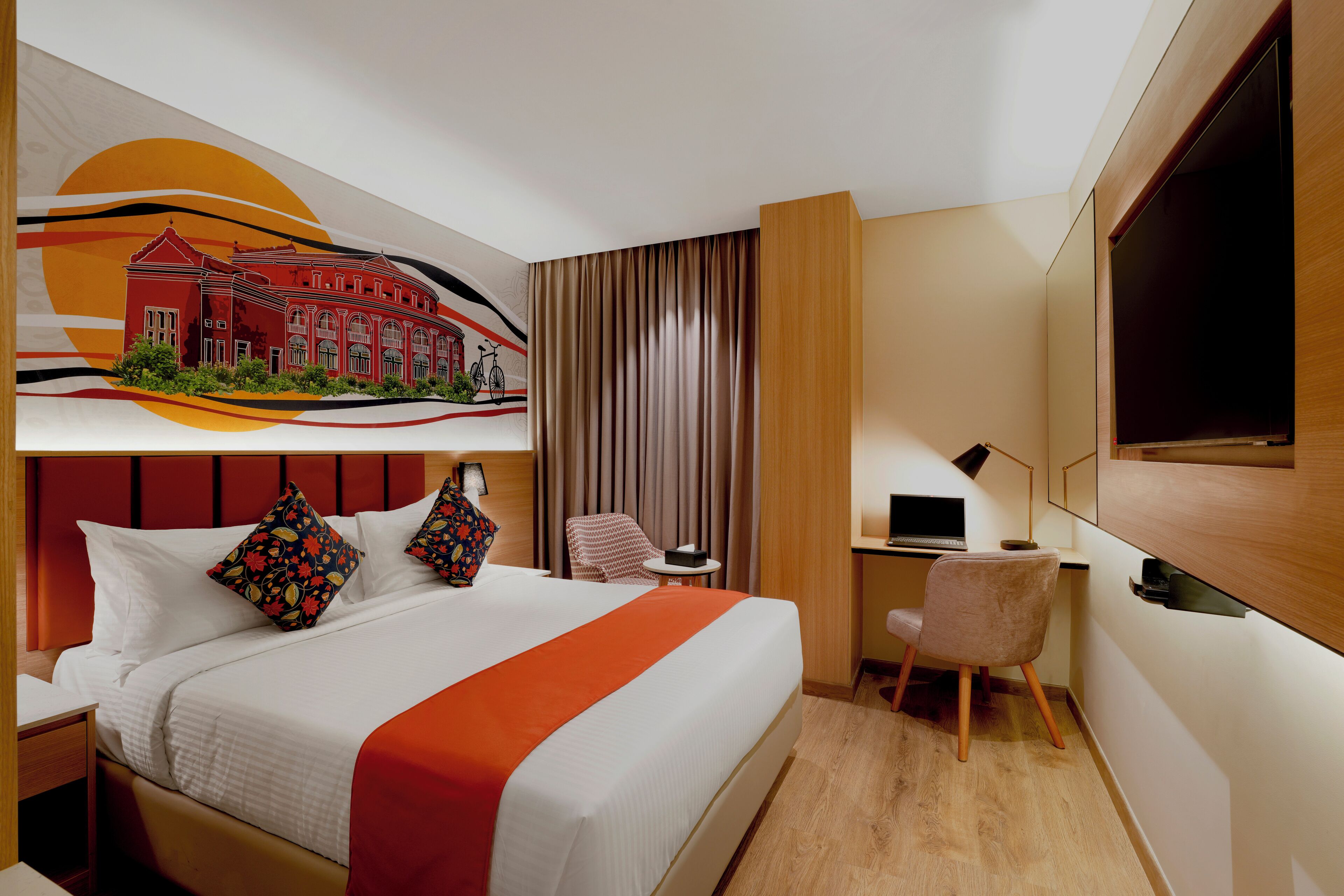 A hotel room with a bed, a desk, a chair, a TV, and a painting on the wall.